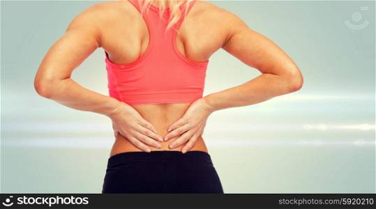 fitness, healthcare and medicine concept - close up of sporty woman touching her back