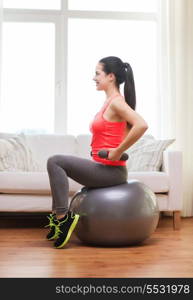 fitness, home and diet concept - smiling girl exercising with fitness ball and dumbbells at home