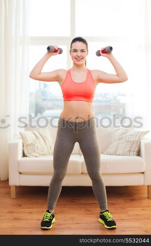 fitness, home and diet concept - smiling redhead girl exercising with heavy dumbbells at home