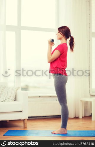 fitness, home and diet concept - smiling redhead girl exercising with heavy dumbbells at home