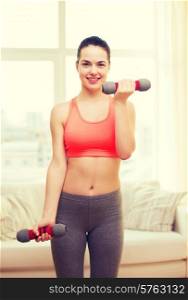 fitness, home and diet concept - smiling redhead girl exercising with heavy dumbbells at home