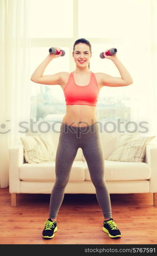 fitness, home and diet concept - smiling redhead girl exercising with heavy dumbbells at home