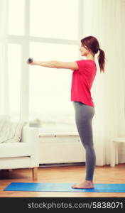 fitness, home and diet concept - smiling redhead girl exercising with heavy dumbbells at home