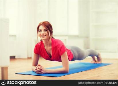 fitness, home and diet concept - smiling redhead teenage girl doing plank at home