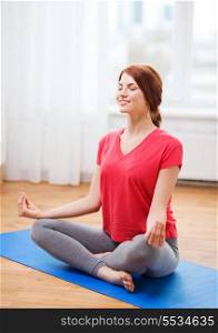 fitness, home and diet concept - smiling redhead teenager meditating at home