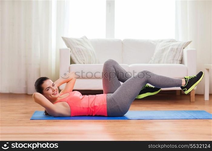 fitness, home and diet concept - smiling teenage girl doing exercise on floor at home