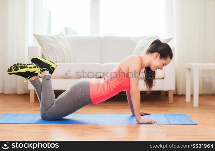 fitness, home and diet concept - smiling teenage girl doing push-ups at home