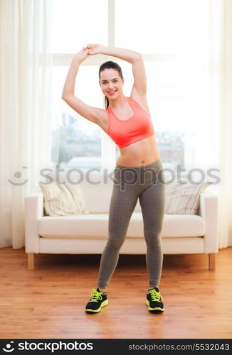 fitness, home and diet concept - smiling teenage girl streching at home