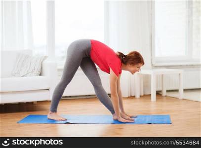 fitness, home and diet concept - smiling teenage girl streching at home