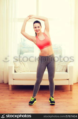 fitness, home and diet concept - smiling teenage girl streching at home