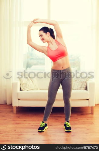 fitness, home and diet concept - smiling teenage girl streching at home