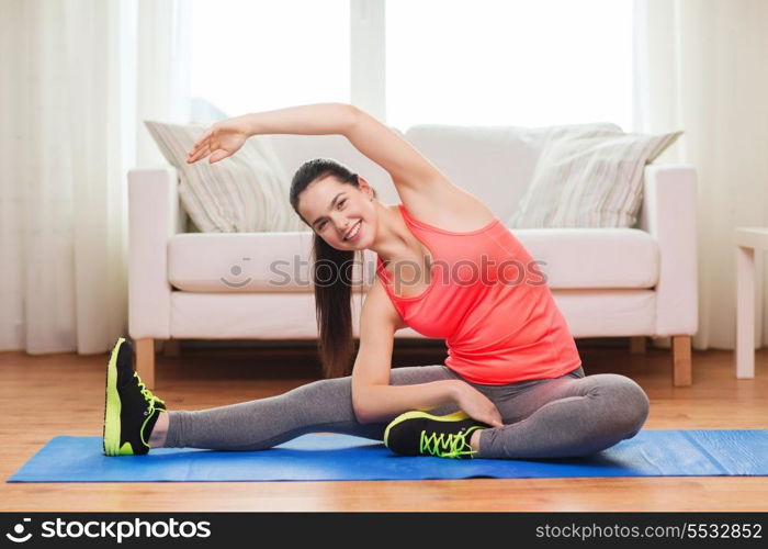 fitness, home and diet concept - smiling teenage girl streching on floor at home