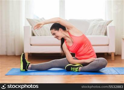 fitness, home and diet concept - smiling teenage girl streching on floor at home