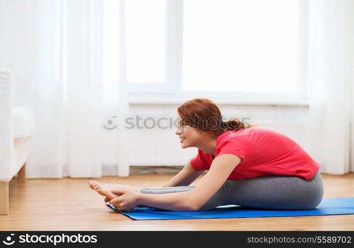 fitness, home and diet concept - smiling teenage girl streching on floor at home