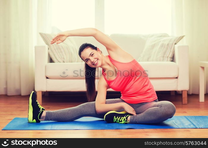 fitness, home and diet concept - smiling teenage girl streching on floor at home