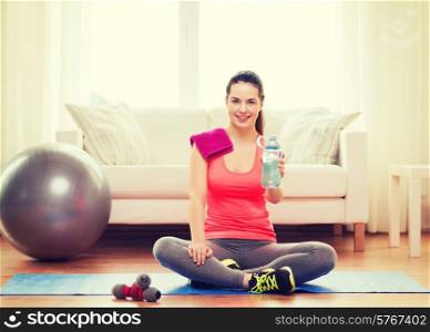 fitness, home and diet concept - smiling teenage girl with bottle of water after exercising at home