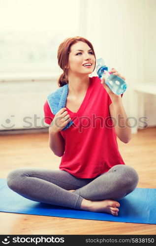 fitness, home and diet concept - smiling teenage girl with bottle of water after exercising at home