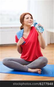 fitness, home and diet concept - smiling teenage girl with bottle of water after exercising at home