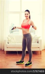 fitness, home and diet concept - smiling teenage girl with skipping rope at home