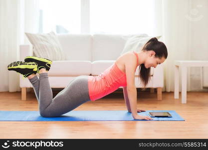 fitness, home, technology and diet concept - smiling teenage girl doing push-ups and looking at tablet pc computer at home