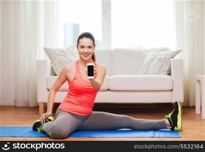 fitness, home, technology and diet concept - smiling teenage girl streching on floor with smartphone at home