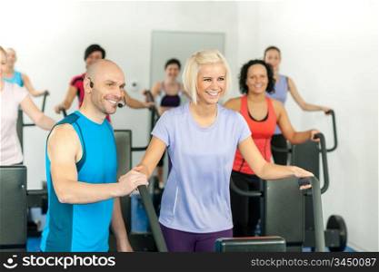 Fitness instructor with gym people exercise on cross-trainer
