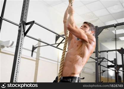 Fitness man doing rope climb exercise in gym. High quality photo.. Fitness man doing rope climb exercise in gym.