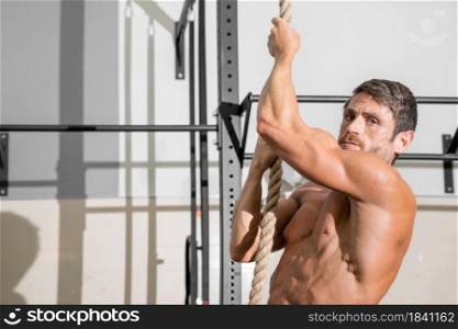 Fitness man doing rope climb exercise in gym. High quality photo.. Fitness man doing rope climb exercise in gym.