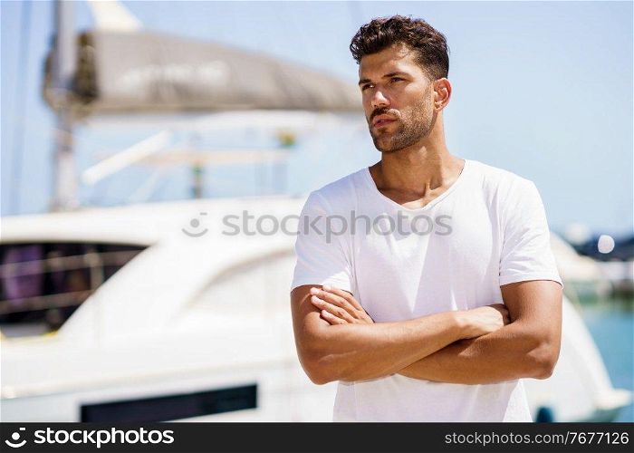 Fitness man, model of fashion, in sportswear outfit posing on waterfront harbour.. Fitness model in sportswear outfit posing on waterfront harbour.