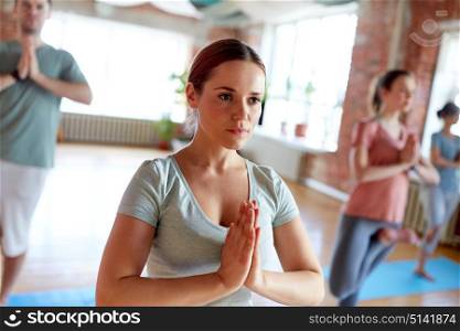 fitness, meditation and healthy lifestyle concept - woman group of people doing yoga in tree pose at studio. group of people doing yoga tree pose at studio