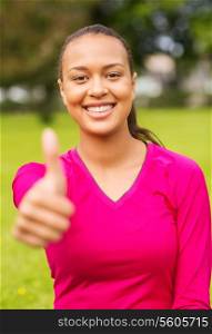 fitness, park, happiness and people concept - portrait of smiling african american woman showing thumbs up outdoors