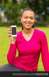 fitness, park, technology and sport concept - smiling african american woman showing smartphone outdoors