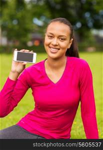 fitness, park, technology and sport concept - smiling african american woman showing smartphone outdoors