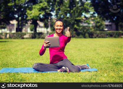 fitness, park, technology, gesture and people concept - smiling african american woman with tablet pc showing thumbs up outdoors