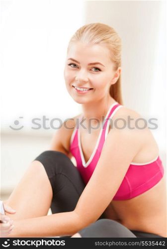 fitness, people and exercise concept - beautiful sporty woman having break in gym