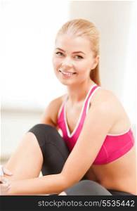 fitness, people and exercise concept - beautiful sporty woman having break in gym