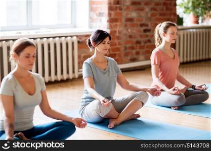 fitness, people and healthy lifestyle concept - group of women meditating in lotus pose at yoga studio. group of women making yoga exercises at studio