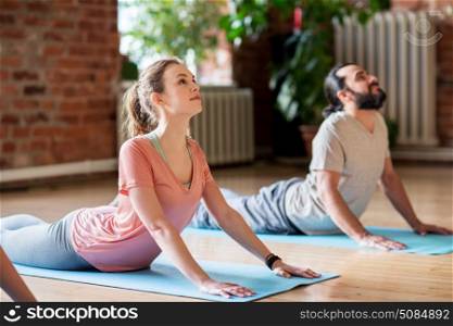 fitness, people and healthy lifestyle concept - man and woman doing cobra pose on mats at yoga studio. man and woman doing yoga cobra pose at studio. man and woman doing yoga cobra pose at studio