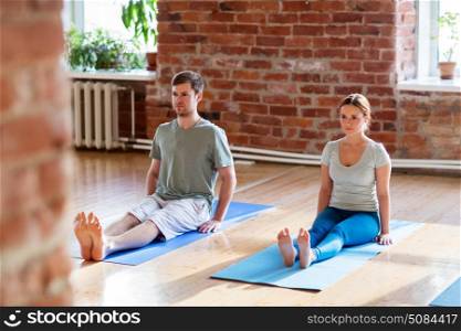 fitness, people and healthy lifestyle concept - man and woman doing yoga seated staff pose on mats at studio. man and woman doing yoga staff pose at studio. man and woman doing yoga staff pose at studio