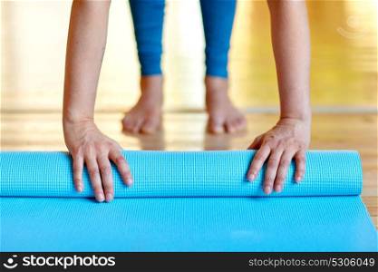 fitness, people and healthy lifestyle concept - woman hands rolling yoga mat at gym or studio. woman hands rolling yoga mat at gym or studio