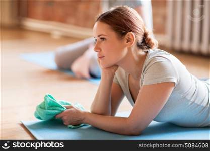 fitness, people and healthy lifestyle concept - woman with towel resting on yoga mat in gym or studio. woman resting on yoga mat in gym or studio. woman resting on yoga mat in gym or studio