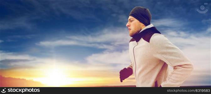fitness, people and healthy lifestyle concept - young man running along winter bridge. man jogging on evening