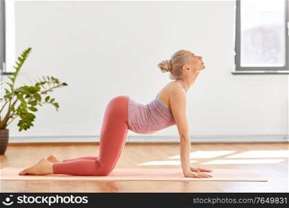 fitness, people and healthy lifestyle concept - young woman doing cow pose at yoga studio. young woman doing cow pose at yoga studio