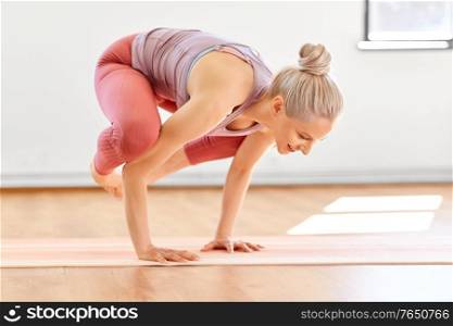 fitness, people and healthy lifestyle concept - young woman doing crane pose at yoga studio. young woman doing crane pose at yoga studio