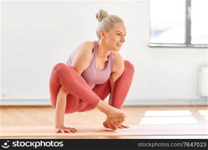 fitness, people and healthy lifestyle concept - young woman doing shoulder-pressing pose at yoga studio. woman doing shoulder-pressing pose at yoga studio