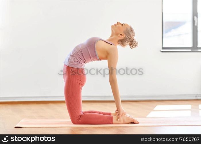 fitness, people and healthy lifestyle concept - young woman doing yoga in camel pose at studio. young woman doing yoga camel pose at studio