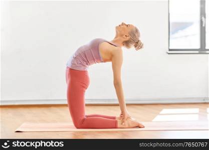 fitness, people and healthy lifestyle concept - young woman doing yoga in camel pose at studio. young woman doing yoga camel pose at studio