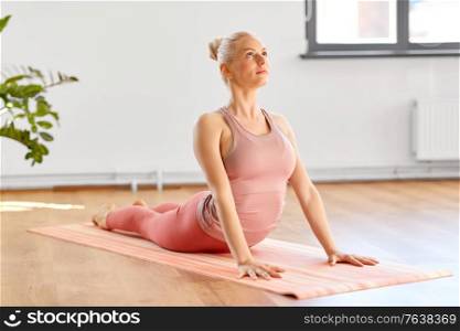 fitness, people and healthy lifestyle concept - young woman doing yoga in cobra pose at home. woman doing yoga in cobra pose at home