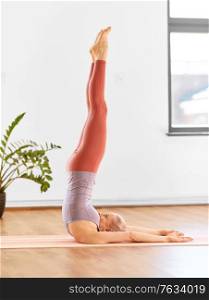 fitness, people and healthy lifestyle concept - young woman doing yoga in shoulderstand at home. woman doing yoga in shoulderstand at home