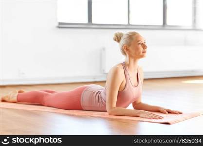 fitness, people and healthy lifestyle concept - young woman doing yoga in sphinx pose at home. woman doing yoga in sphinx pose at home
